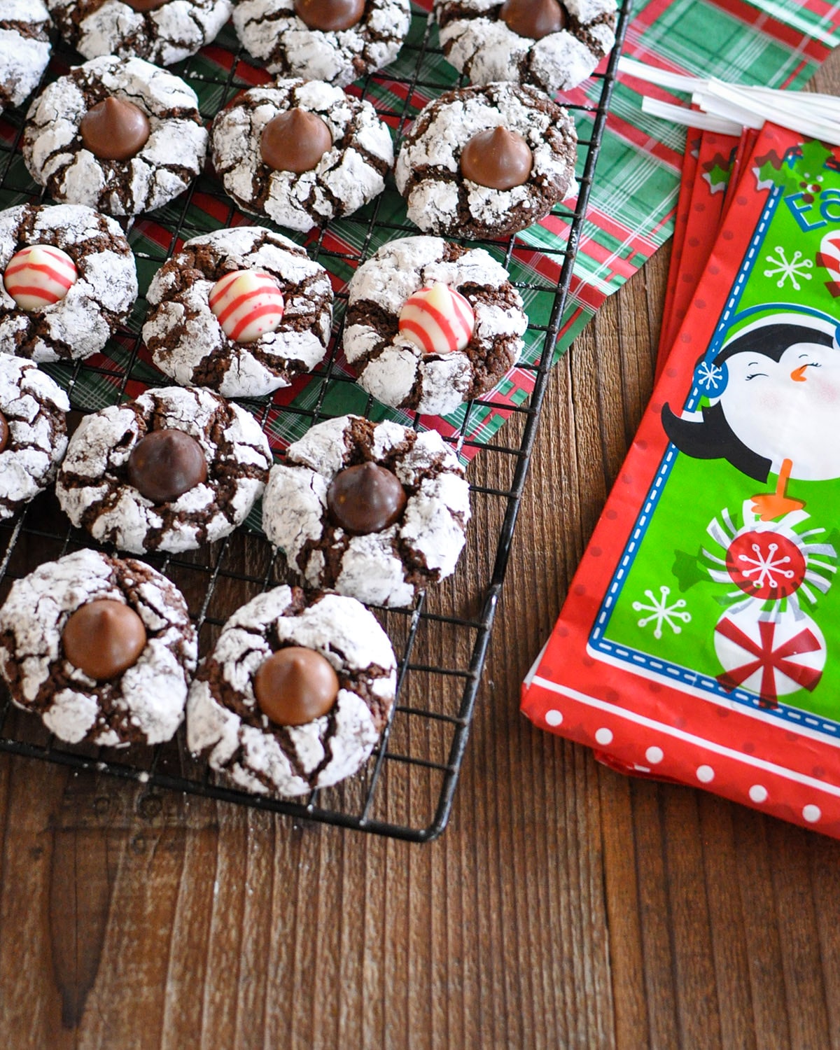 chocolate crinkle cookies with a holiday hershey kiss in the middle on a black rack