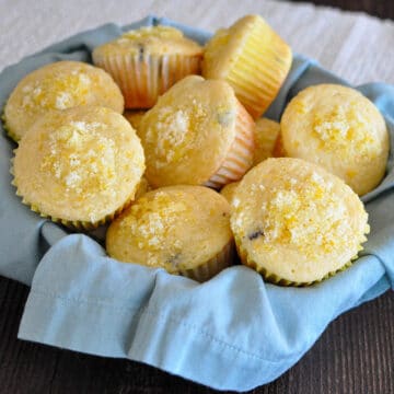 orange muffins in a basket lined with a blue napkin
