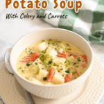A bowl of homemade potato soup with carrots and celery, garnished with herbs, sits invitingly on a plate with a spoon nearby.