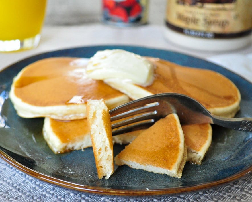 several plain pancakes on a plate with butter on top