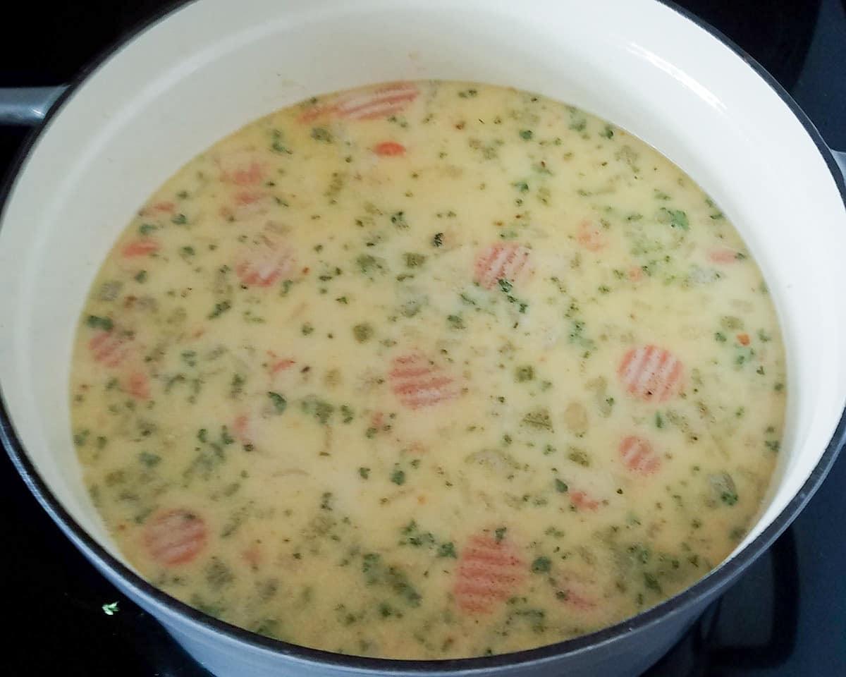 creamy potato soup with carrots and celery cooking in a stock pot