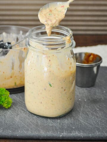 a jar full of chipotle flavored ranch dressing on a black cutting board