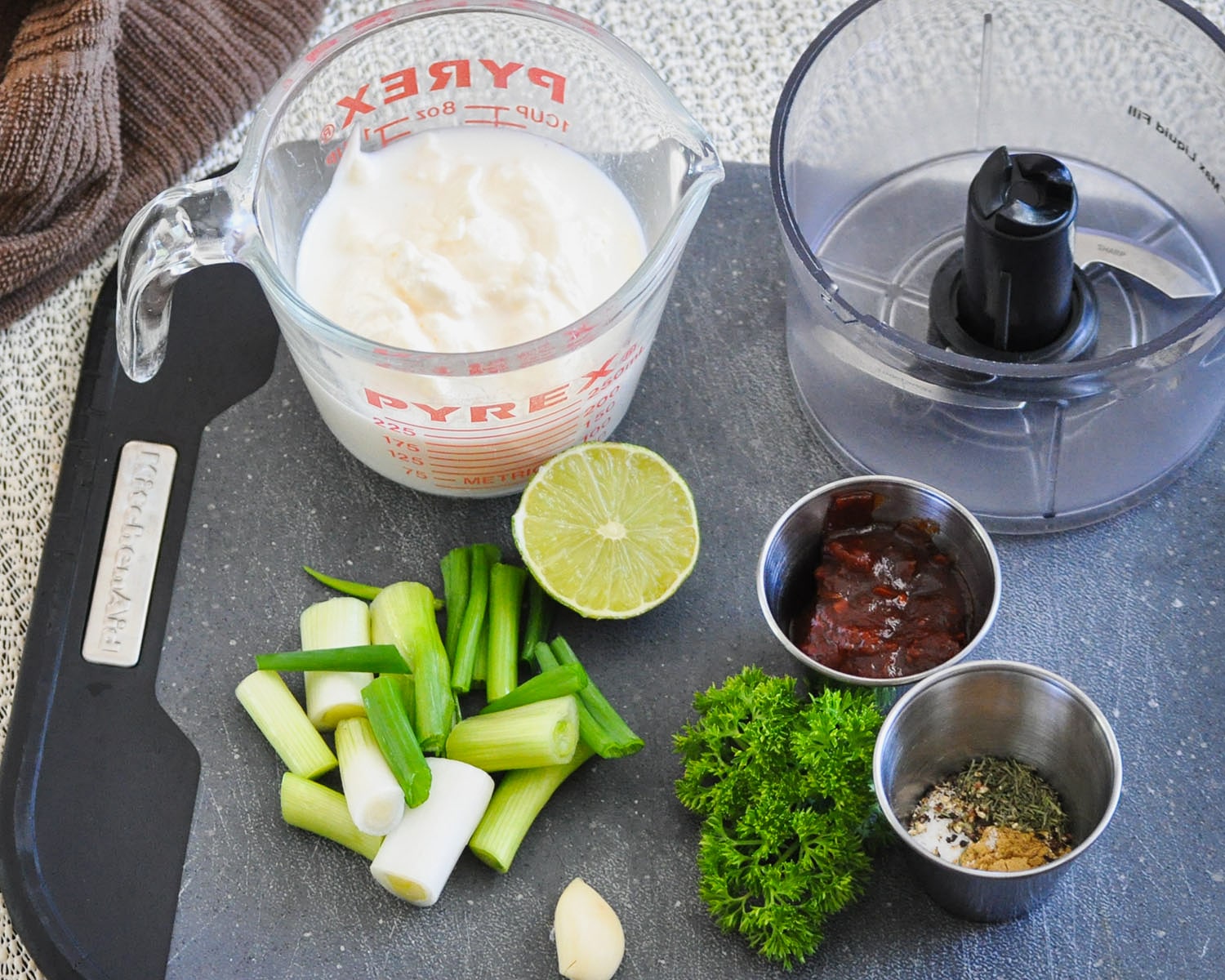 milk, mayo, green onion, garlic, spices, chipotle in adobo sauce, lime on a black cutting board