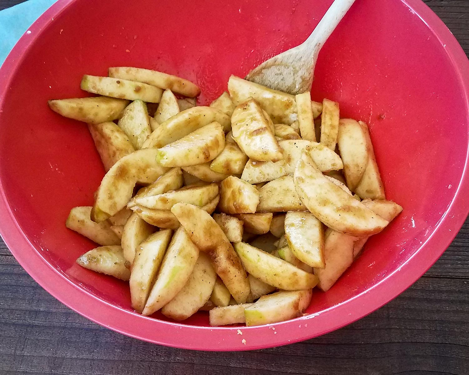 sliced apples with brown sugar and nutmeg in a red bowl