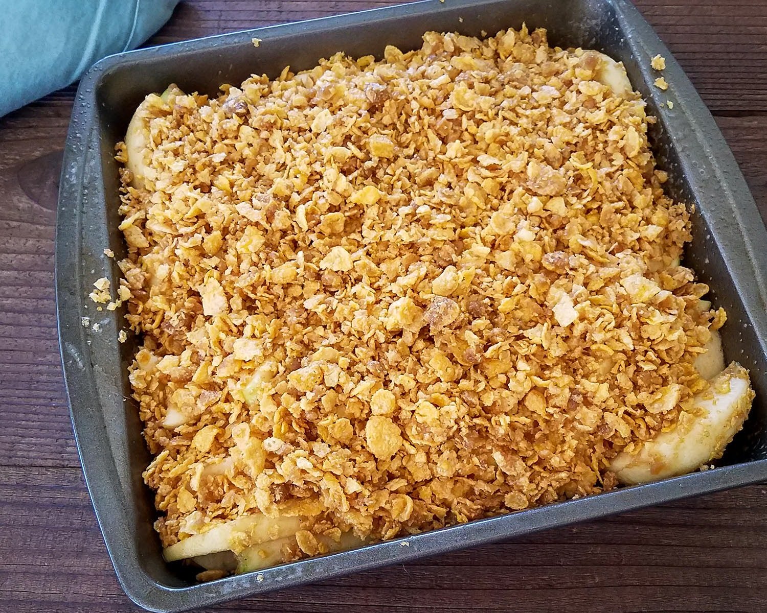 sliced apples in a baking pan with a corn flakes crumb topping