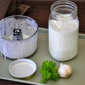 Jar of homemade ranch dressing next to parsley and garlic