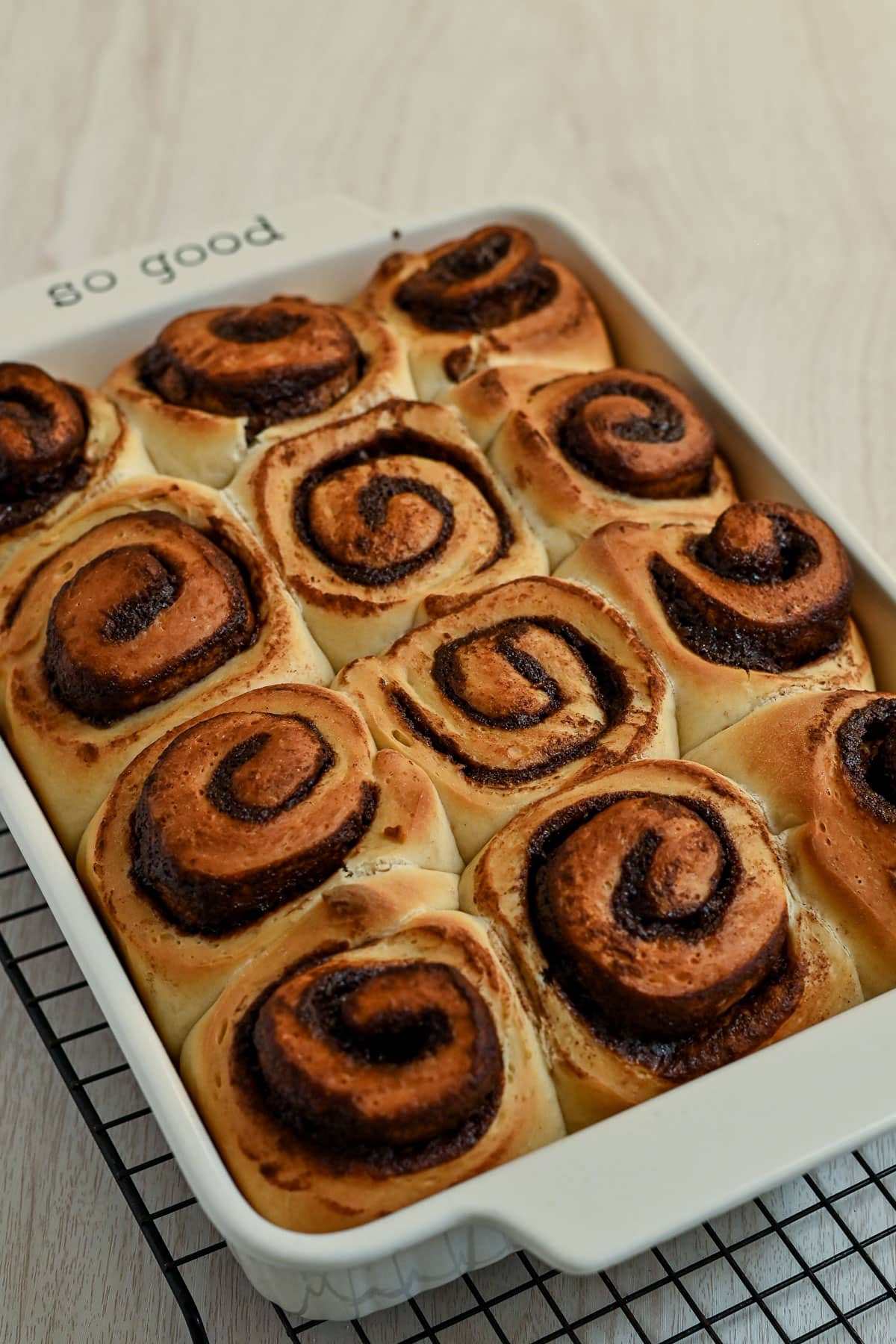 A baking dish filled with freshly baked chocolate cinnamon rolls, resting on a cooling rack.