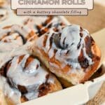 Close-up of decadent Chocolate Cinnamon Rolls in a baking dish, generously topped with white icing, with text overlay describing these indulgent cinnamon rolls.