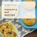 a pineapple muffin split in two laying on a lace table runner next to the pan of muffins and recipe card