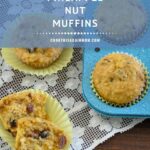 a pineapple muffin split in two laying on a lace table runner next to the pan of muffins and recipe card