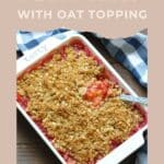 Baked plum oatmeal crisp with oat topping in a white dish, served with a spoon on a blue plaid towel—a delicious plum dessert perfect for summer.