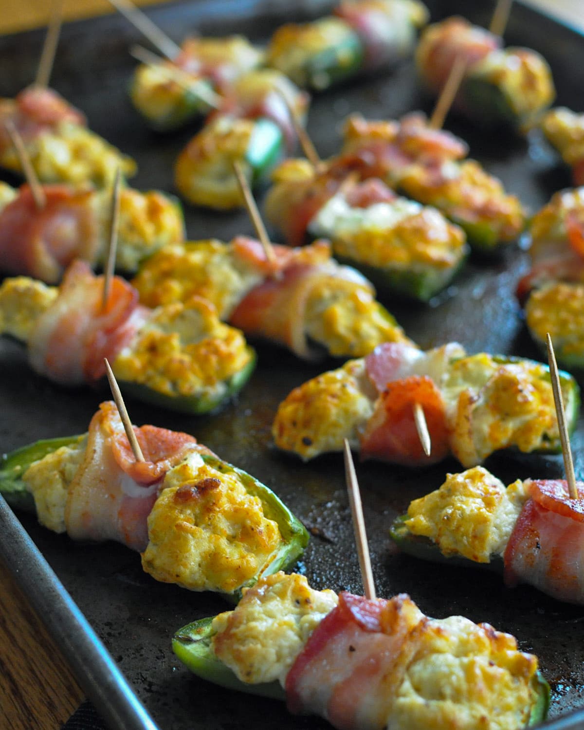 a baking sheet with bacon wrapped stuffed jalapeno appetizers