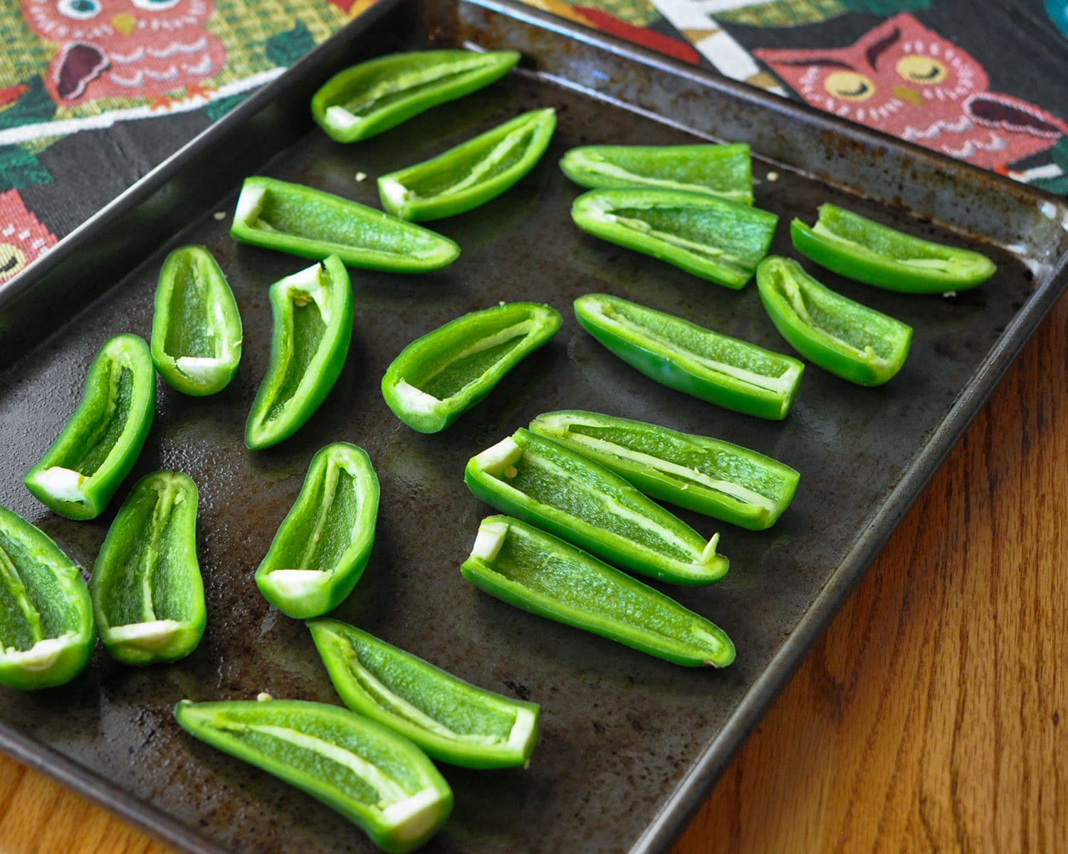 a baking pan full of jalapeno peppers cut in half lengthwise