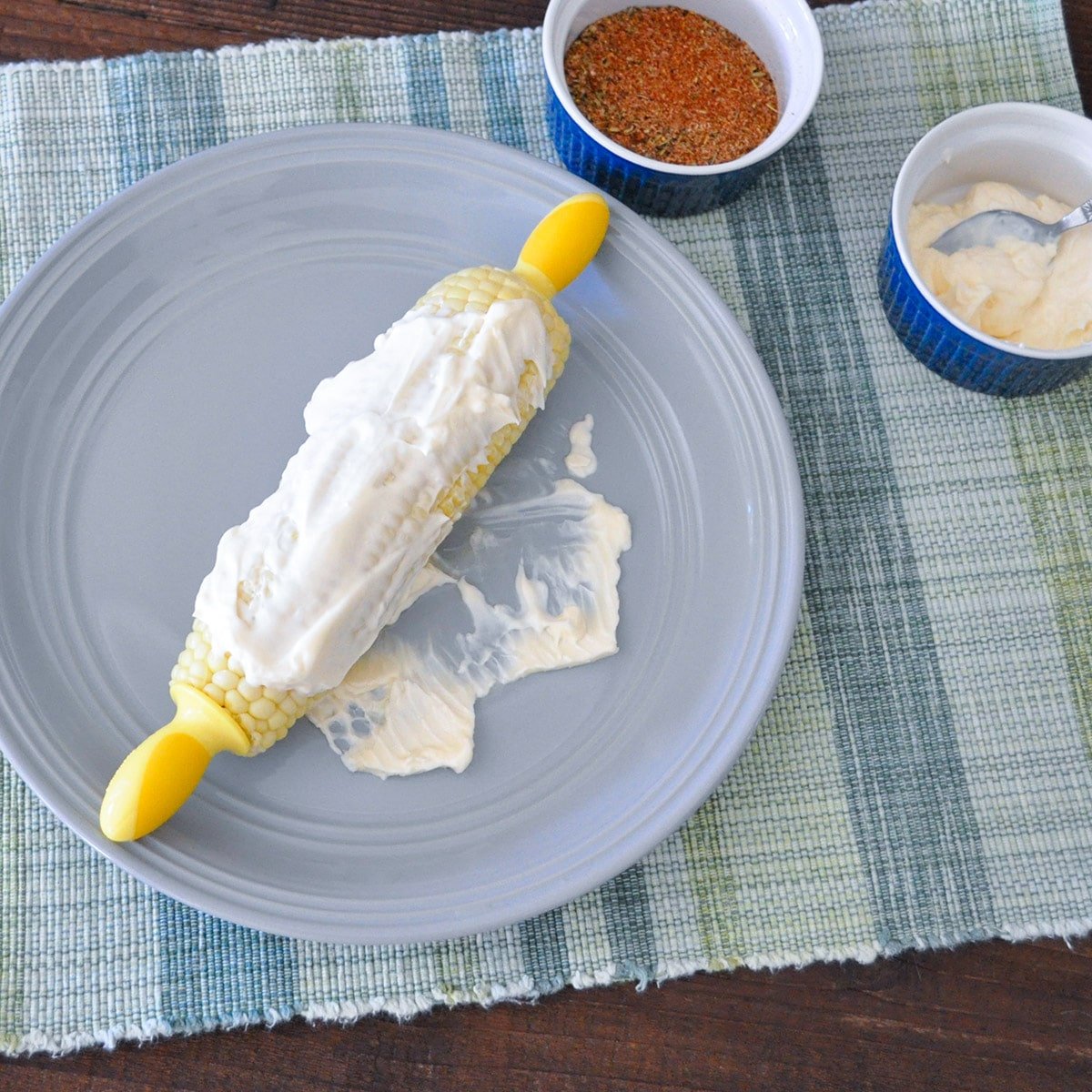 corn covered with mayonnaise on a gray plate