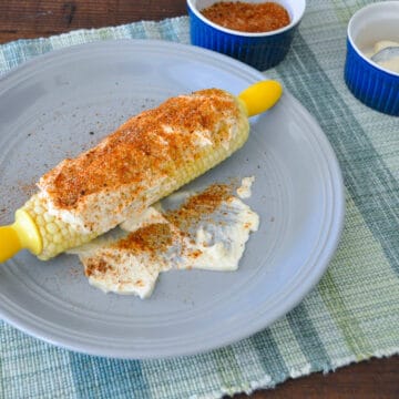 corn on the cob with spices on a gray plate
