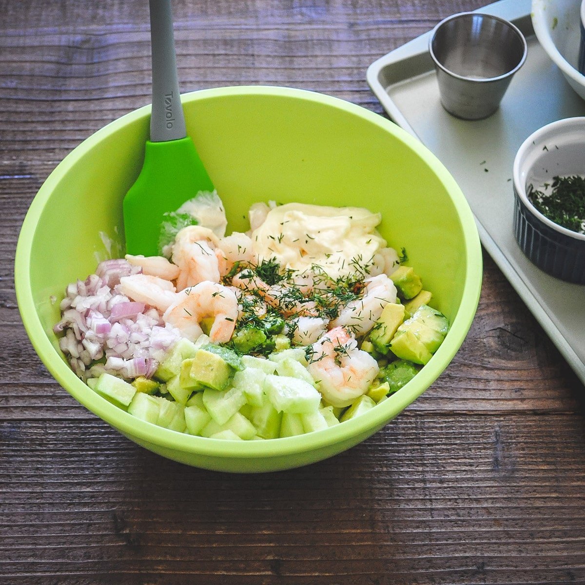 shrimp with chopped cucumber, avocado, fresh dill shallot and mayo in a green bowl before mixing together