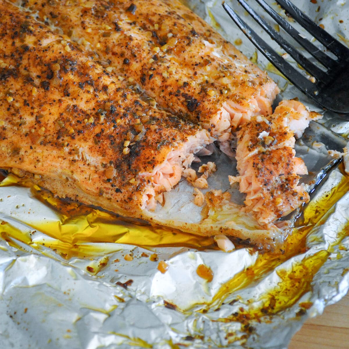 a close up photo a grilled salmon in foil next to a fork