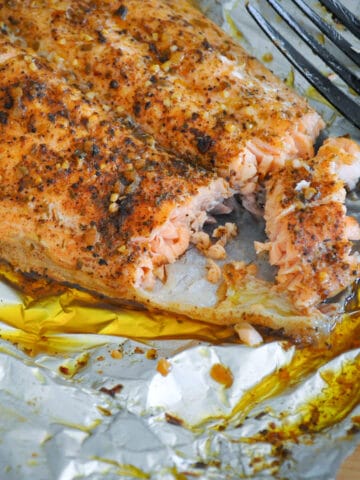 a close up photo a grilled salmon in foil next to a fork