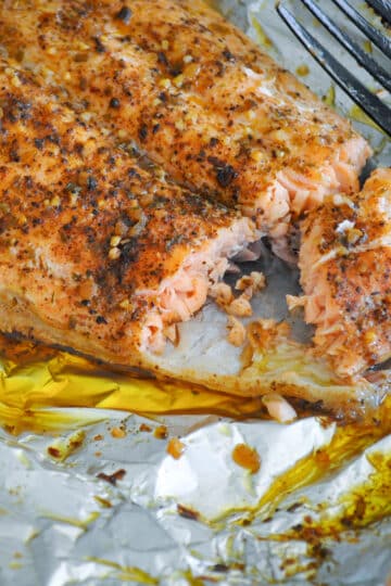 a close up photo a grilled salmon in foil next to a fork