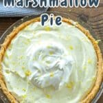 Lemon Marshmallow Pie topped with whipped cream and lemon zest sits enticingly on a wooden table.