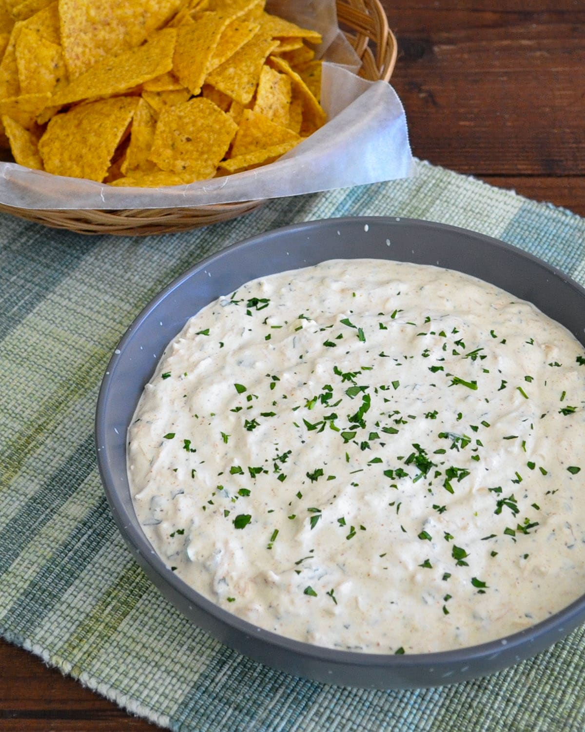 curry chicken dip in a gray bowl next to a basket of tortilla chips