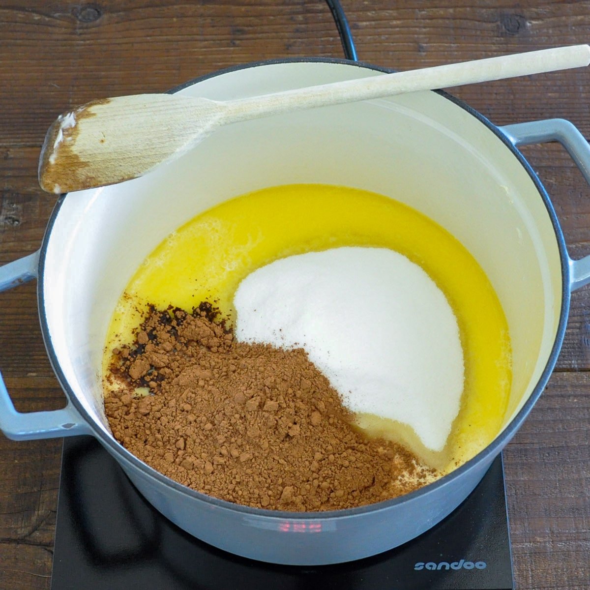 Butter melting in a large pan with sugar, cocoa, and milk