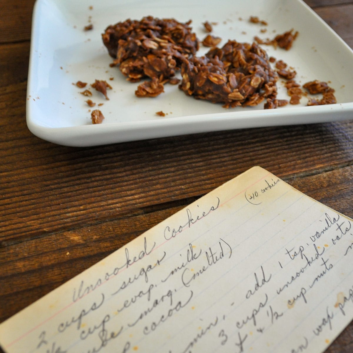 a couple of chocolate cookies on a plate next to a handwritten recipe card