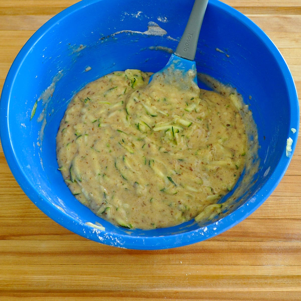 Mixed zucchini muffin batter in a blue bowl