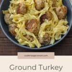 A bowl of pasta topped with Ground Turkey Swedish Meatballs and garnished with fresh herbs, served on a rustic wooden table.