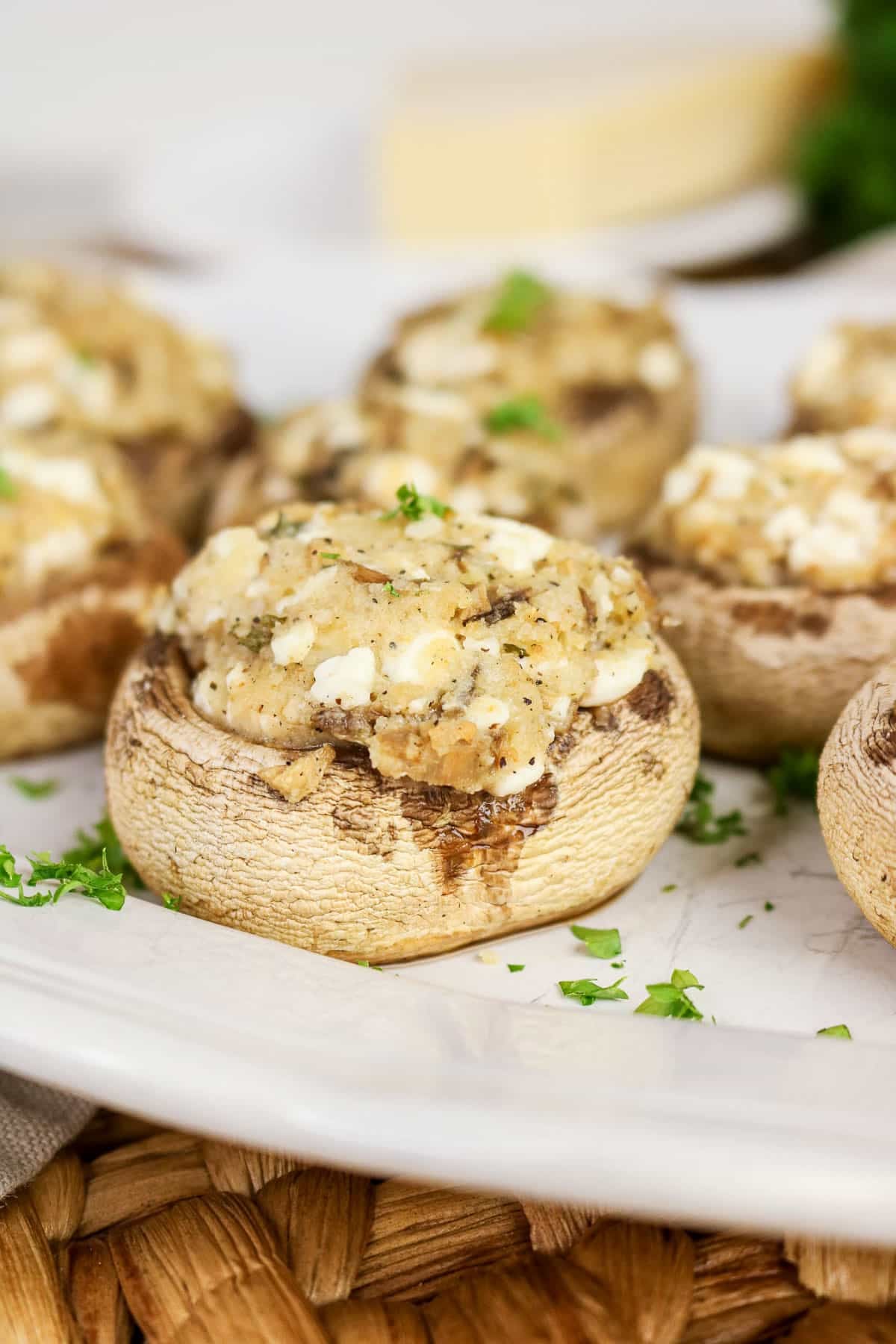 Easy Stuffed Mushrooms topped with melted cheese and herbs, served on a white plate with parsley garnish.