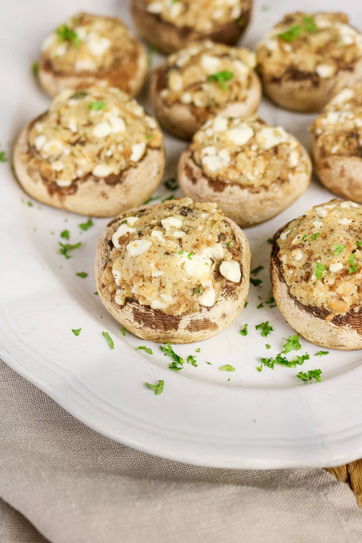 Easy Stuffed Mushrooms with a crumbly filling, garnished with chopped herbs, arranged on a white plate for a simple yet elegant appetizer.