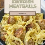 A bowl of pasta with Ground Turkey Swedish Meatballs, garnished with herbs, sits on a wooden table with a napkin.