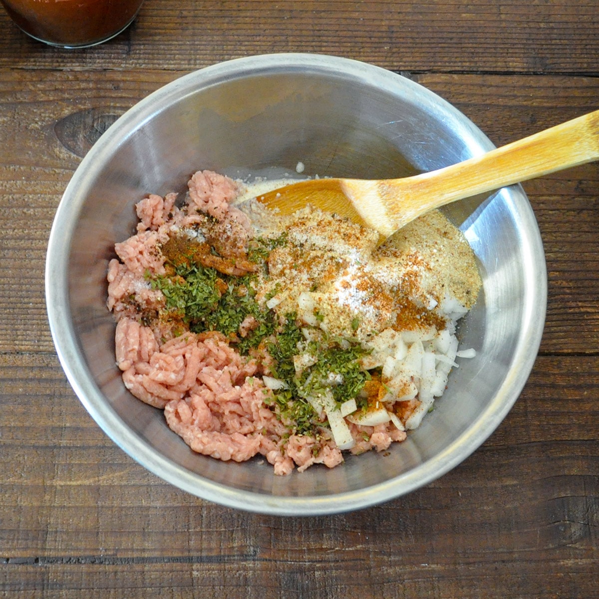 raw ground turkey, onion, bread crumbs, and spices in a metal bowl