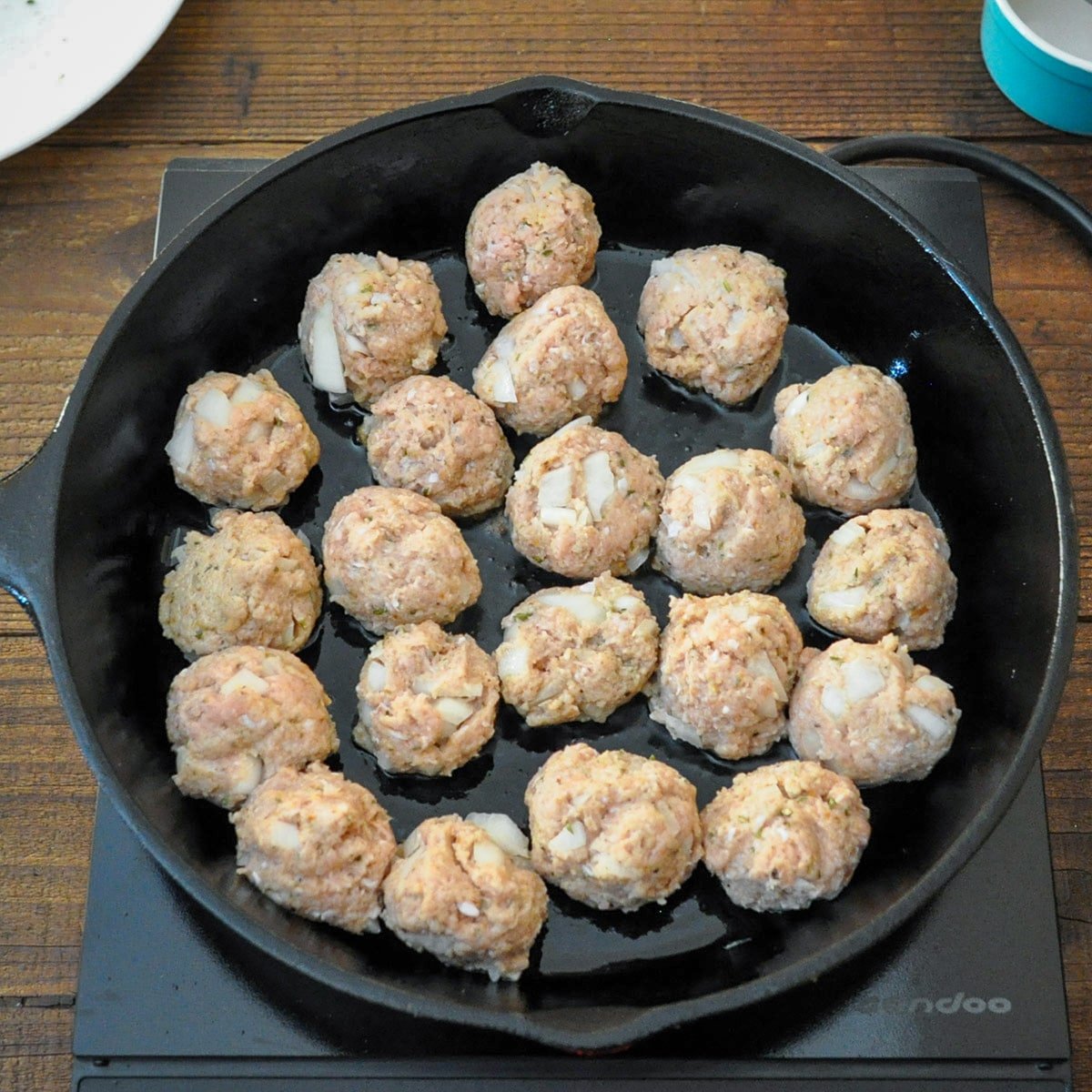 raw meatballs that were just placed in a cast iron skillet