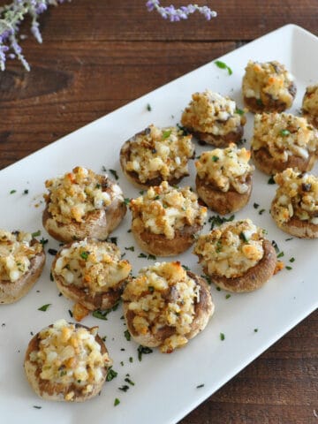 stuffed mushrooms on a white platter next to a bundle of lavendar