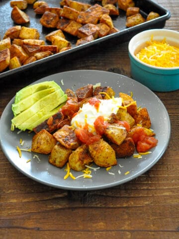 taco roasted potatoes on a gray plate with avocado sour cream cheese and salsa