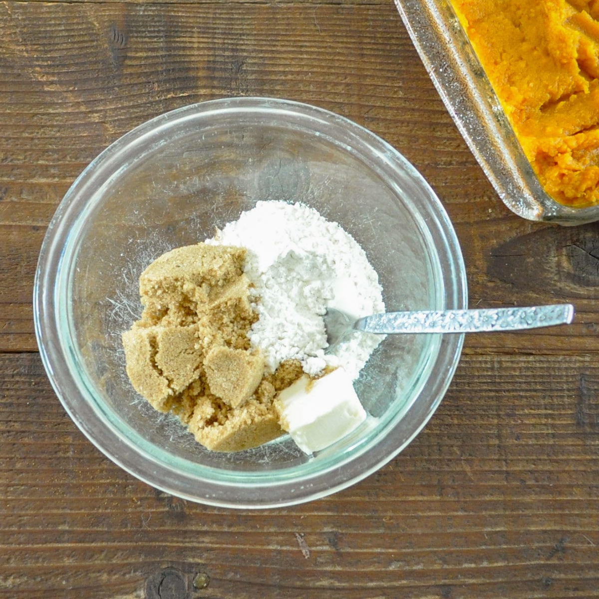 a small bowl with flour, brown sugar, and butter next to mashed sweet potatoes