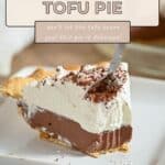 A slice of Chocolate Tofu Pie with whipped cream and chocolate shavings sits on a white plate, fork digging in—an irresistible treat that's proof this recipe is pure bliss.