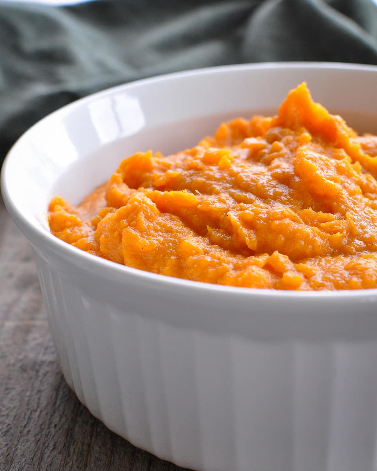 a white casserole bowl filled with mashed sweet potatoes