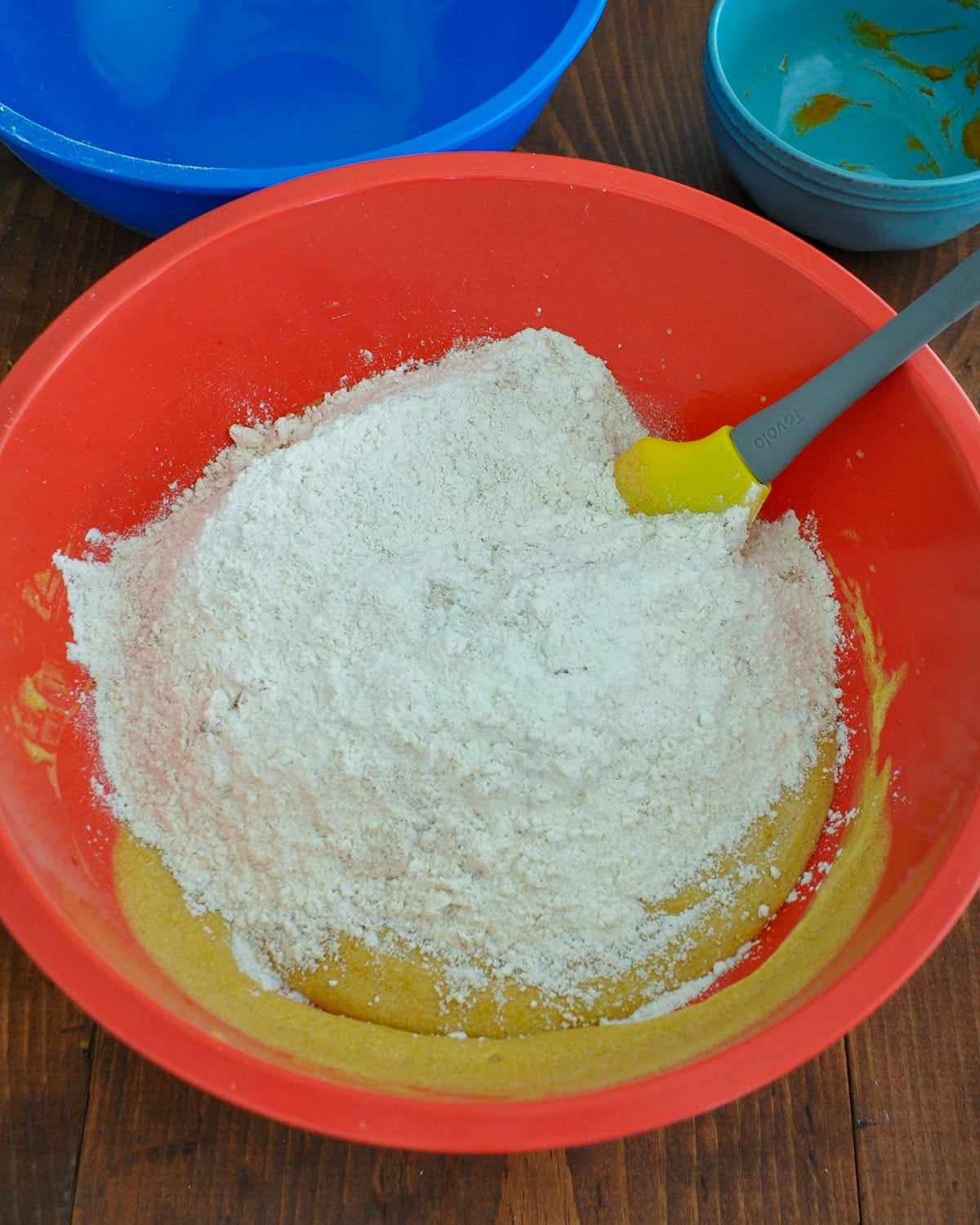 flour and pumpkin spices added to the wet cookie dough ingredients in a large bowl