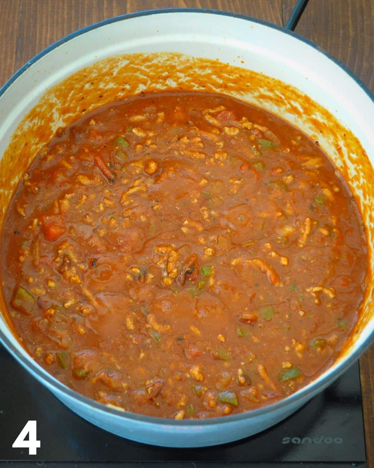 Tomato sauce added to seasoned ground turkey for chili.