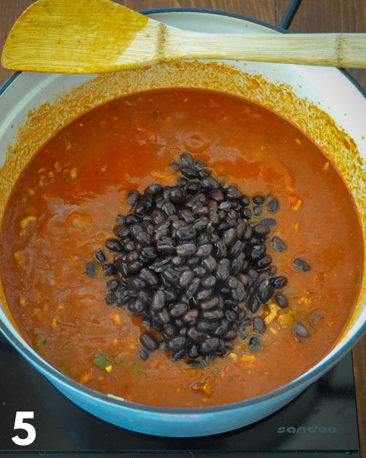 Black beans added to ground turkey chili while it is cooking.