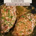 Two pork chops with garlic white wine sauce, garnished with parsley, simmering in a black skillet for a flavorful and savory meal.