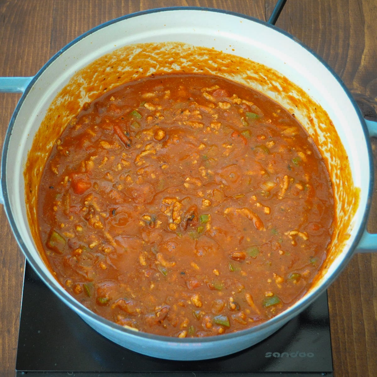 diced tomatoes and tomato sauce added to ground turkey chipotle chili in a large pot