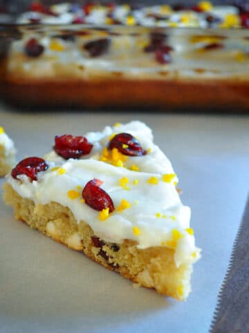 closeup photo of a cranberry bliss bar with the baking dish in the background
