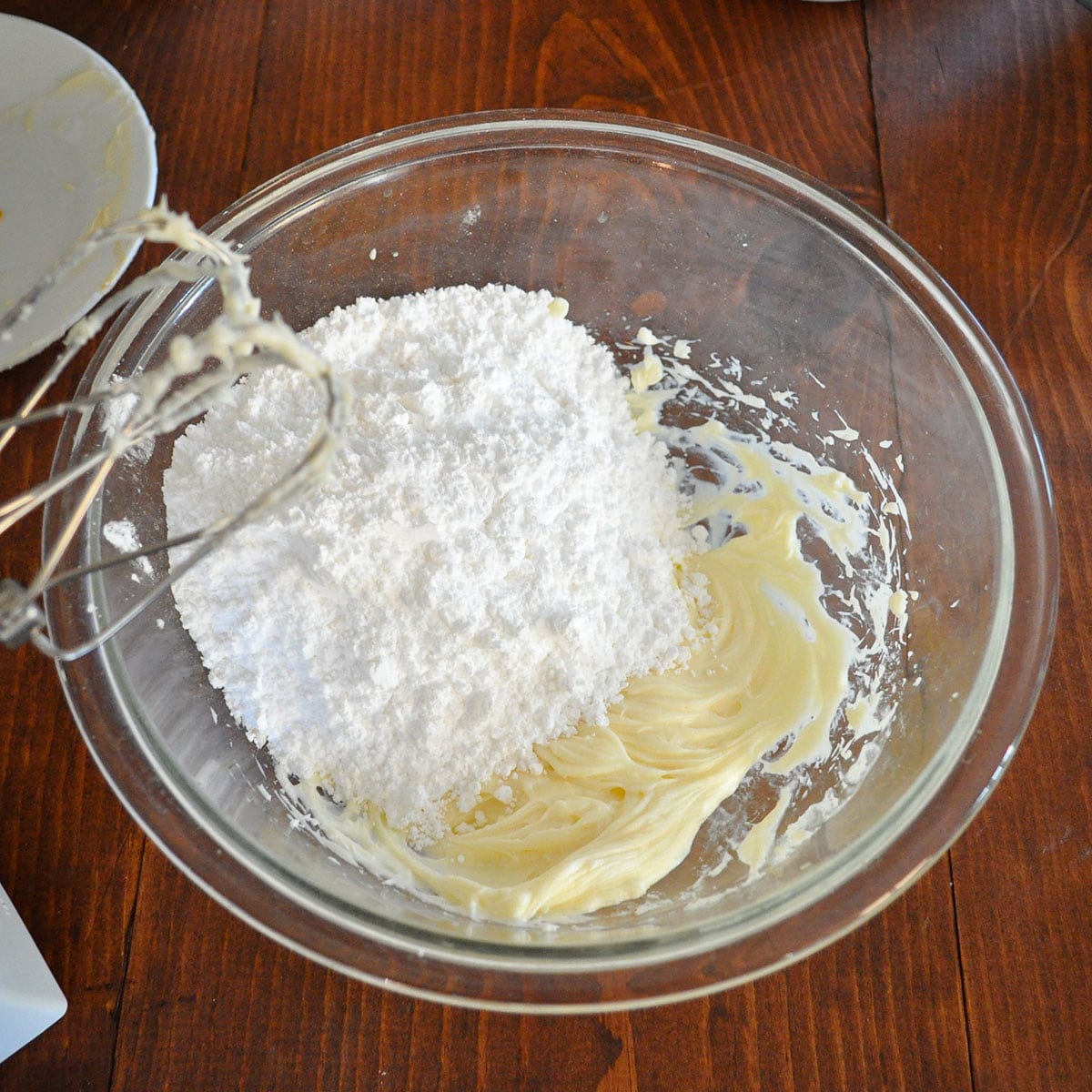 cream cheese creamed with butter in a glass bowl with powdered sugar added