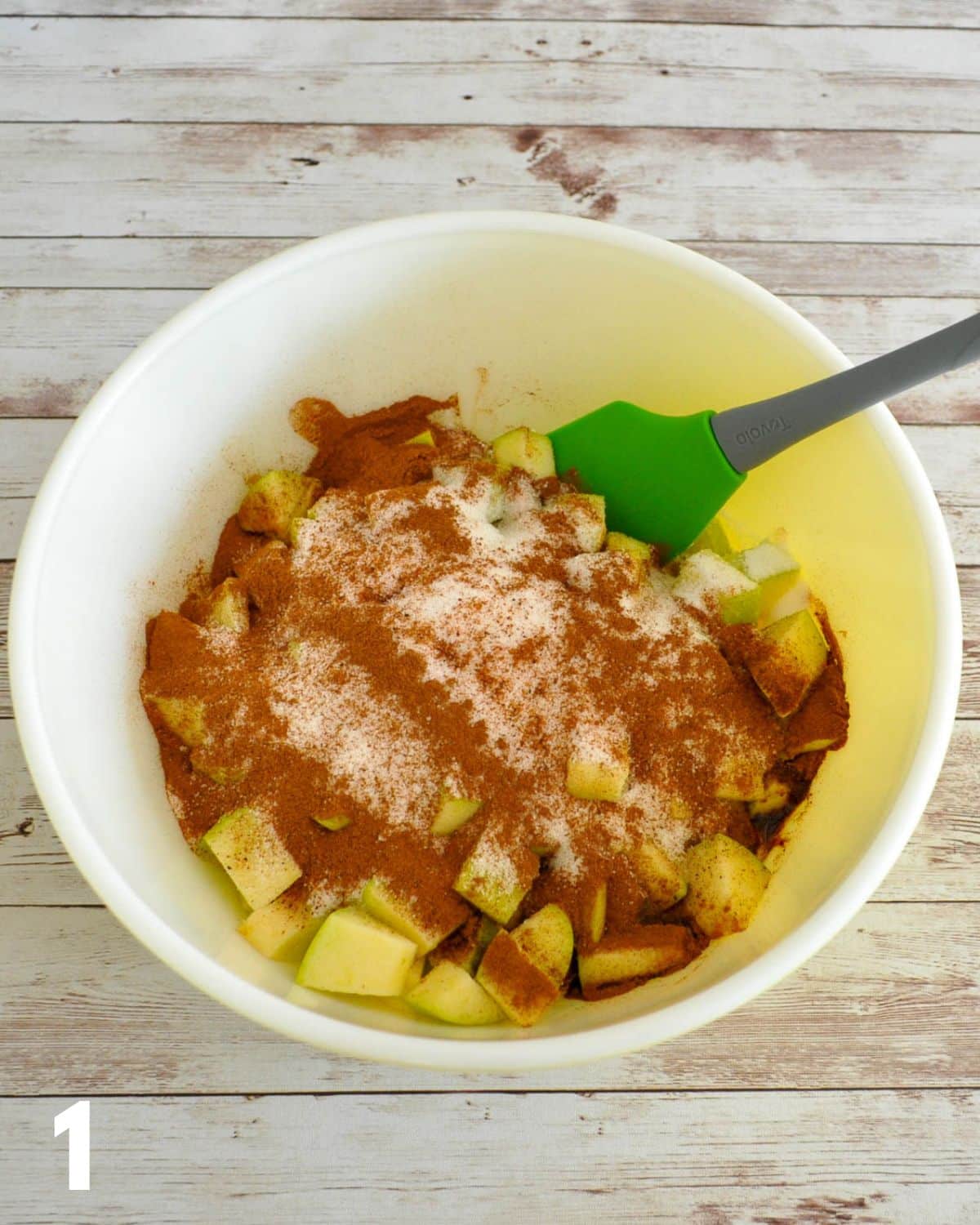 Cubed granny smith apples in a bowl with cinnamon and nutmeg. 