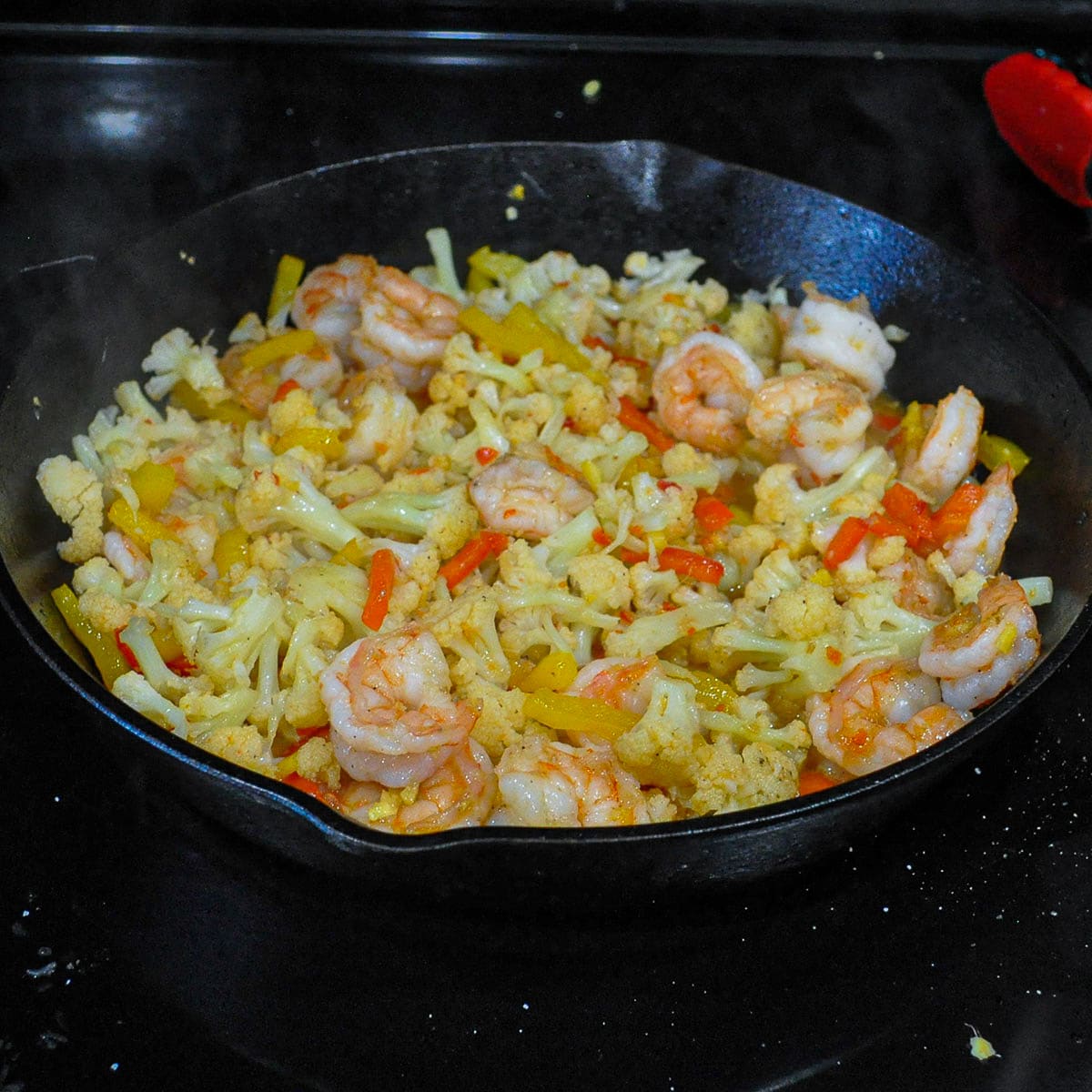 shrimp with cauliflower and peppers cooking in a skillet