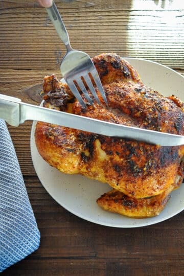 whole roasted chicken being sliced with a knife
