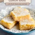 Three Tart Lemon Bars dusted with powdered sugar are stacked on a blue plate with a lace doily underneath.